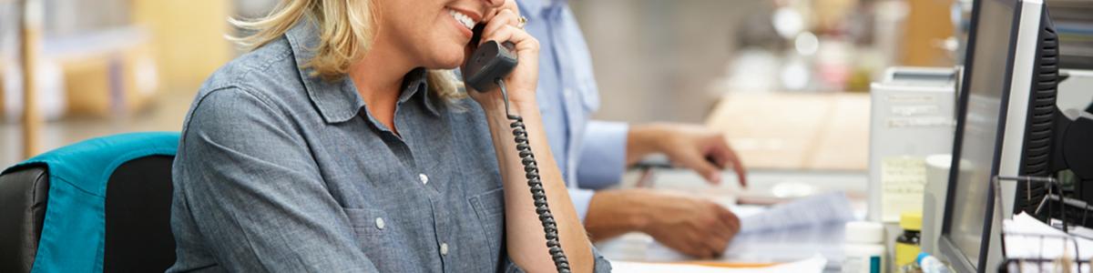 Businesswoman Working At Desk In Warehouse Smiling